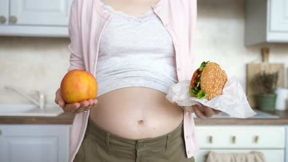 Pregnant Woman Holding A Burger And An Apple – Healthy Vs Unhealthy Food