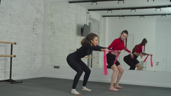 Black Fit Woman Training Banded Squat with Fitness Instructor