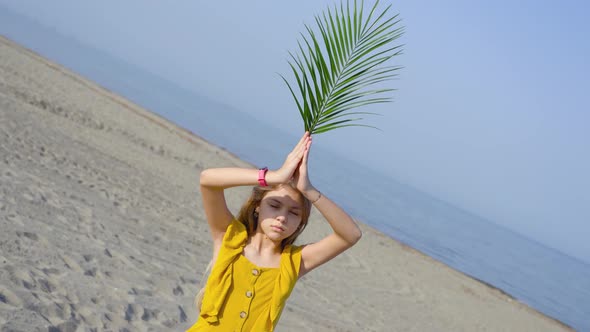 Girl Holds in Hand a Green Sheet of Flowers on the Sea