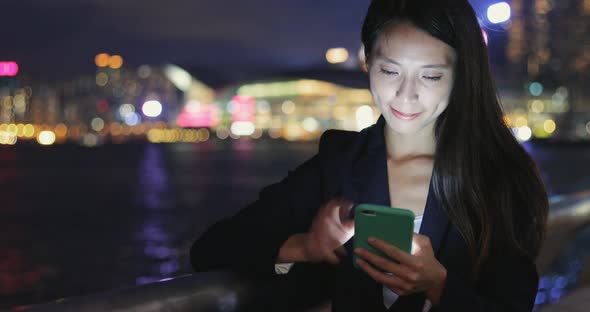 Business woman looking at mobile phone at night 