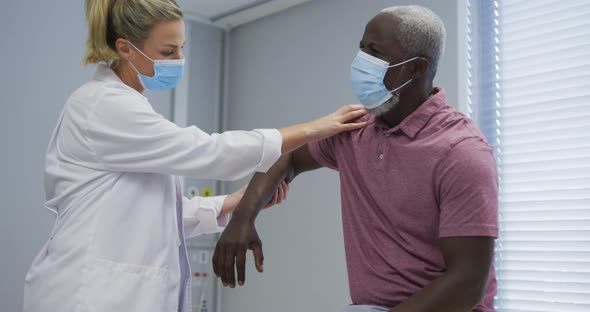 Diverse femaleorthopedic doctor examining male patient in face masks