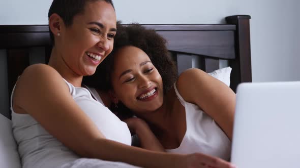 Lesbian couple using laptop in bedroom