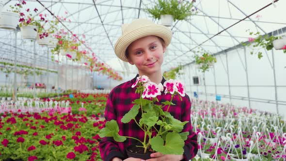 Child Holding a Flower Pot in His Hand Looks Excitedly in the Camera