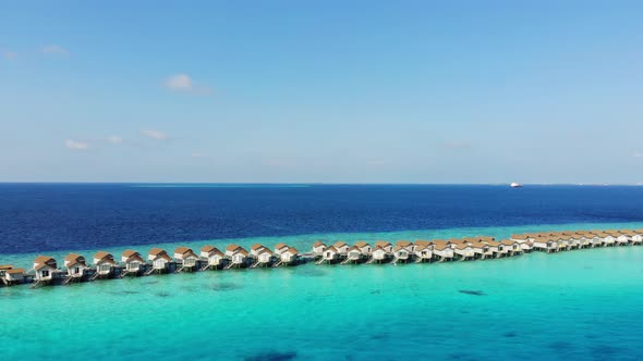 Aerial view villas over water on tropical island resort in Maldives with turquoise sea