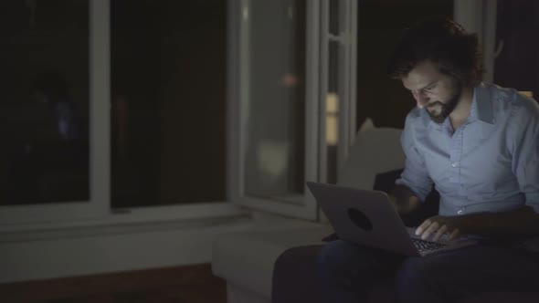 Concentrated Young Man Working on Tablet at Home, Typing Message