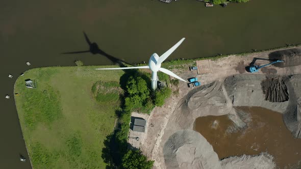 A Wind Engine Structure Rotating Its Blades Near The Gouwe Canal With View Of A Hydraulic Digger On