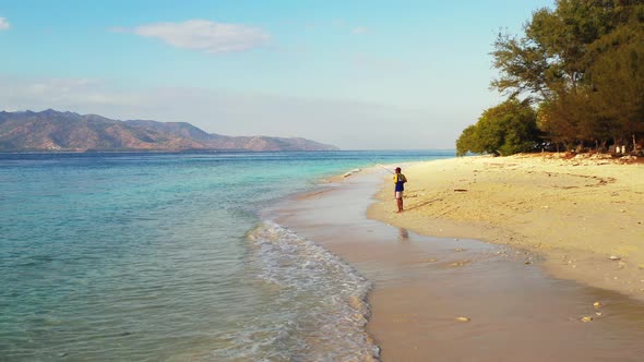 Angling for cute man on a journey enjoys life on beach on sunny blue and white sand background 4K