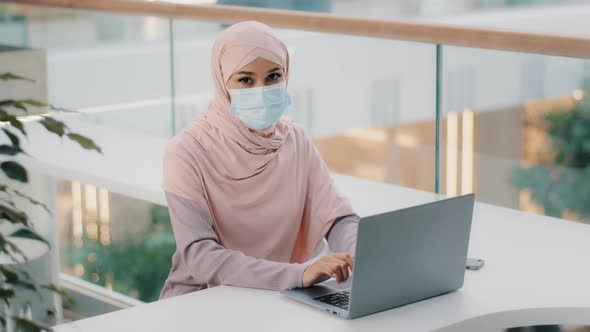 Young Arab Woman User in Hijab Businesswoman in Medical Mask Works on Laptop Testing New Computer