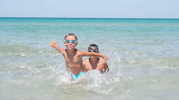 Cute Little Happy Child in Water Glasses Playing and Splashing in the Azure Sea Water with His Older