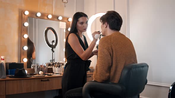 Woman Make Up Artist Applying a Nude Lipstick on the Lips of Male Model