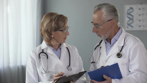 Experienced Male and Female Doctors Comparing Results, Consulting on Diagnosis