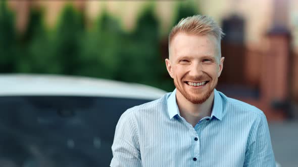 Young Successful Male Businessman Posing Outdoor at Car Background Looking at Camera