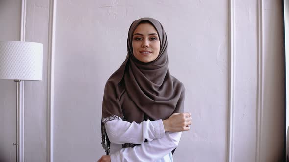 Muslim Woman Look at the Camera and Adjust Brown Hijab Smiling