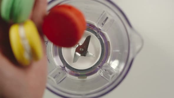 Several macaroons fall into mixer from a hand