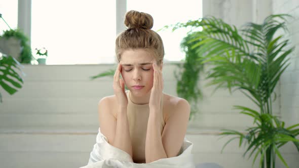 Young Brunette Woman with Bun on Her Head is Experiencing Severe Headaches