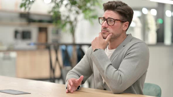 Anxious Middle Aged Man Sitting and Thinking in Office 