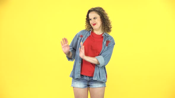 Girl Strictly Gesturing with Hands Shape Meaning Denial Saying NO. Yellow Background at Studio