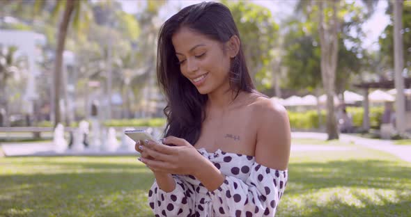 Pleasant Asian Woman with Open Shoulder Texting in Smartphone with Smile