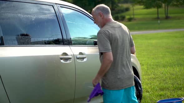 Dancing crazy man slapping his car with soapy wash rags.