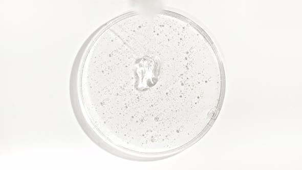 Transparent Cosmetic Gel Fluid Dripping Into the Glass Bowl of Petri alt