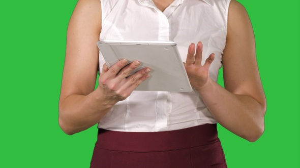 Woman holding digital tablet and using it while walking