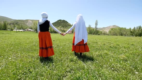 Women In Traditional Dress Walking In The Meadow In Village