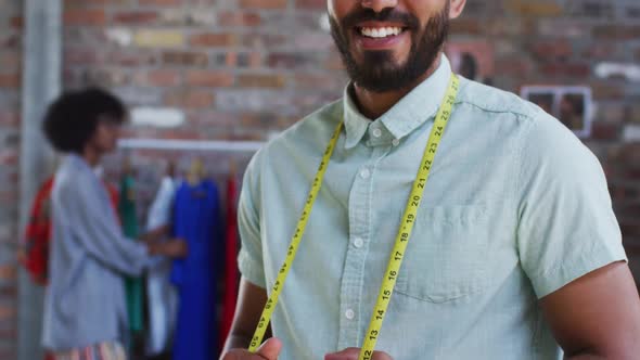 Happy mixed race male fashion designer looking at camera and smiling