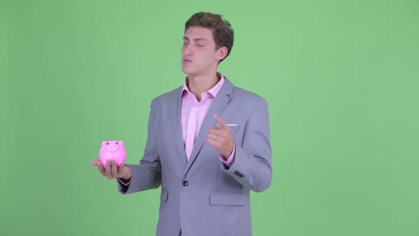 Happy Young Businessman Talking While Holding Piggy Bank