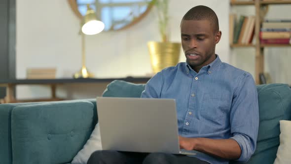 Young African Man with Laptop Coughing on Sofa 