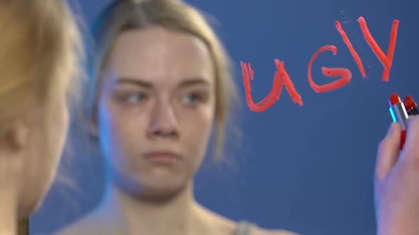 Upset Teen Girl Writing With Lipstick Word Ugly on Mirror Low Self-Esteem