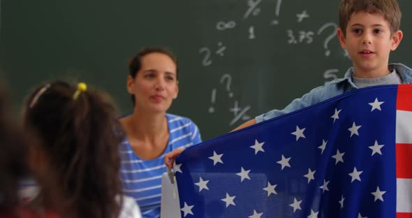 Front view of Caucasian schoolboy explaining about American flag in the classroom 4k