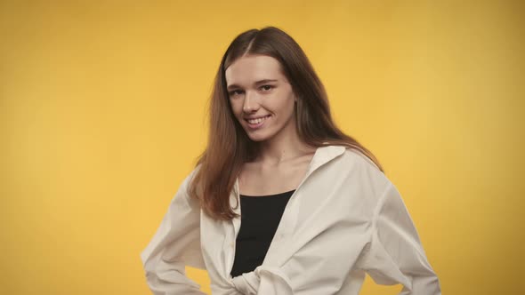 Young Adult Caucasian Woman is Turning and Shaking Her Hair on a Bright Yellow Background