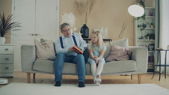 Little Girl and Her Grandfather Are Reading a Book