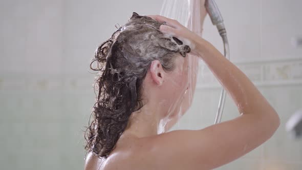 Side View of Slim Young Caucasian Woman Washing Shampoo Off Hair in Slow Motion Taking Shower at