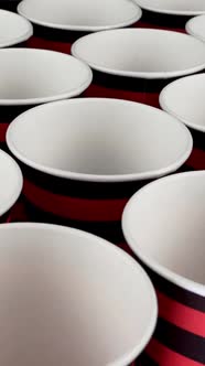 Row Red and Black Disposable Paper Cup for Coffee or Hot Beverage on Dark Backdrop Rotate Slowly