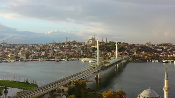 Aerial drone of a cloudy sunrise morning in Istanbul Turkey as seagulls fly across Halic Metro Bridg