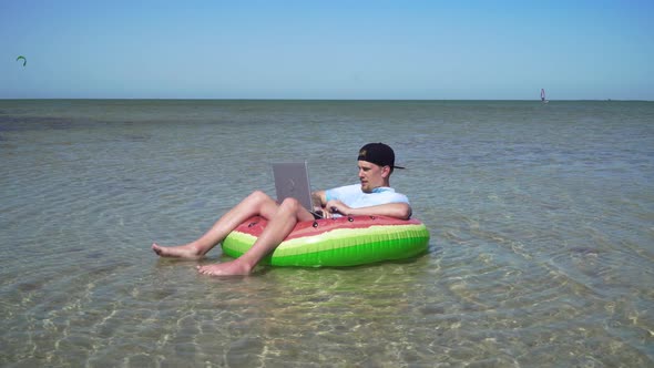 A Young Business Person Is Enthusiastically Working Behind a Laptop Swaying on the Waves of Sea