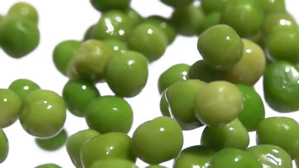 Super Closeup of the Green Peas Bouncing Up and Down on the White Background
