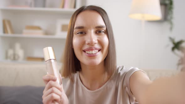 Woman Showing Bottle With Face Foundation