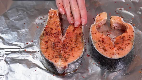 Raw salmon Fillet or red fish steak. Seasoning salmon steak. Girl spreads ground pepper and olive
