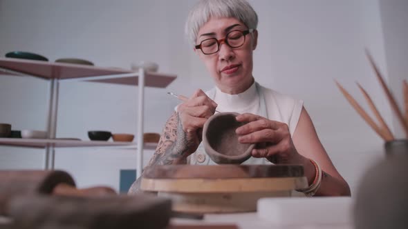 Asian elderly woman enjoying pottery work at home.