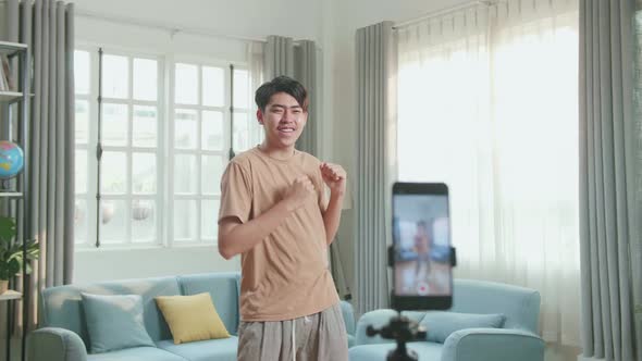 Asian Man Dancing While Shooting Video Content For Social Networks With A Smartphone Camera