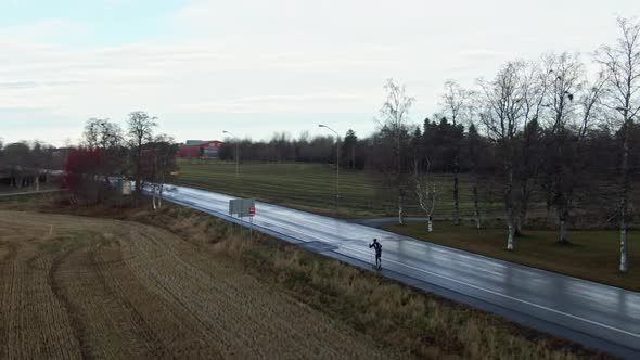 Man Skiing Down Wet Countryside Road Near Ostersund, Sweden During Dusk. 4K Drone.