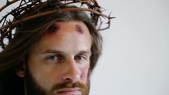 Jesus in a Crown of Thorns with Wounds on Face Looks Into the Camera