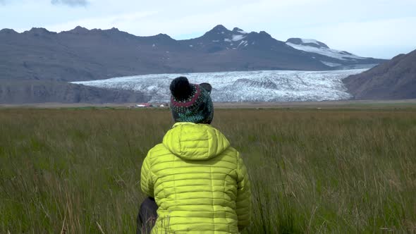 A Woman Sits in the Grass and Enjoys the Beautiful Nature of Iceland