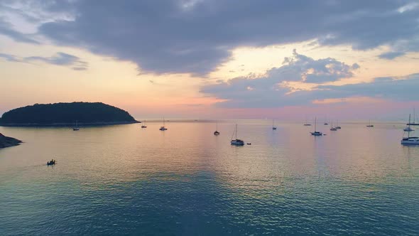 Colorful sunset above the sea surface with sail boats. Aerial view drone fly over Phuket sea