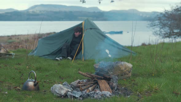 Young man camp site on island carrying supplies puts down makeshift fish trap