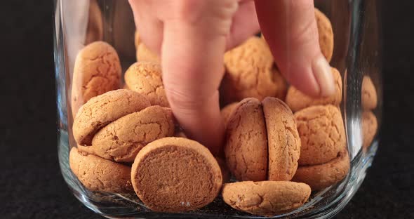 Hand taking a biscuit from a glass jar