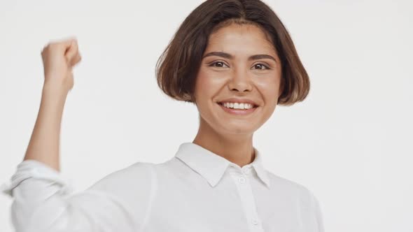 Young Beautiful Brunette East Asian Female in Shirt Smiling Showing Ok with Thumb on White