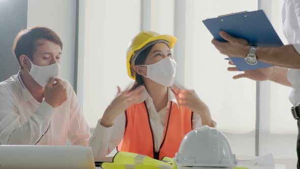 engineer caucasian male and asian female serious concentrate meeting with mask protection